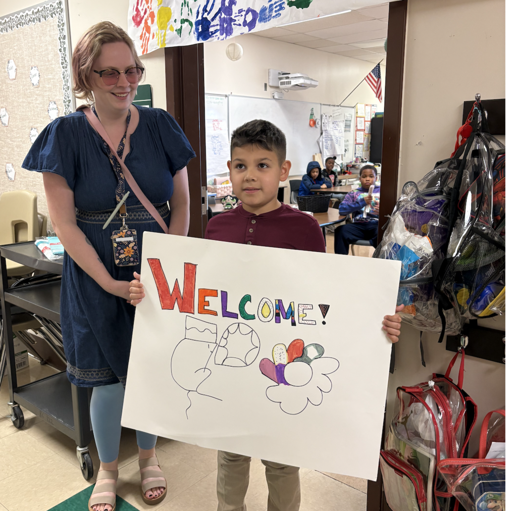Student holding a sign next to a teacher
