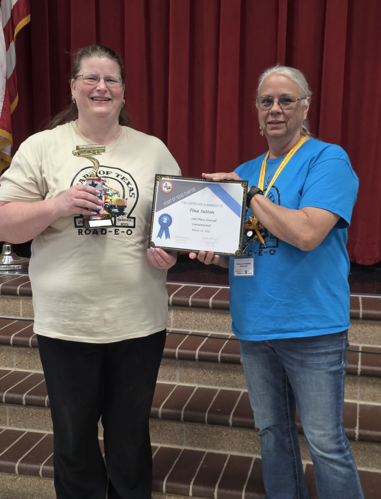 woman holding trophy and certificate smiling next to woman