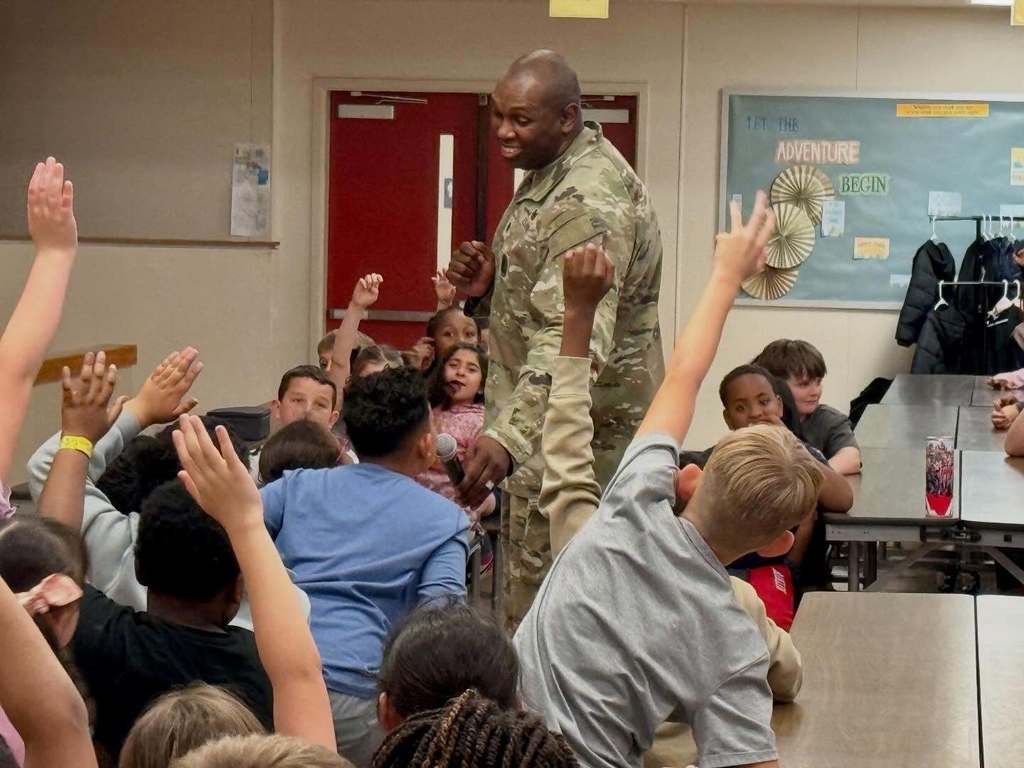 man in military uniform talking to a group of student 
