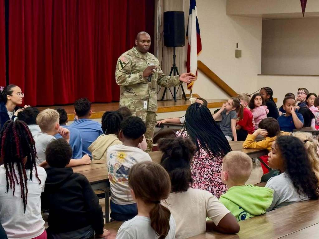 man in military uniform talking to a group of student 