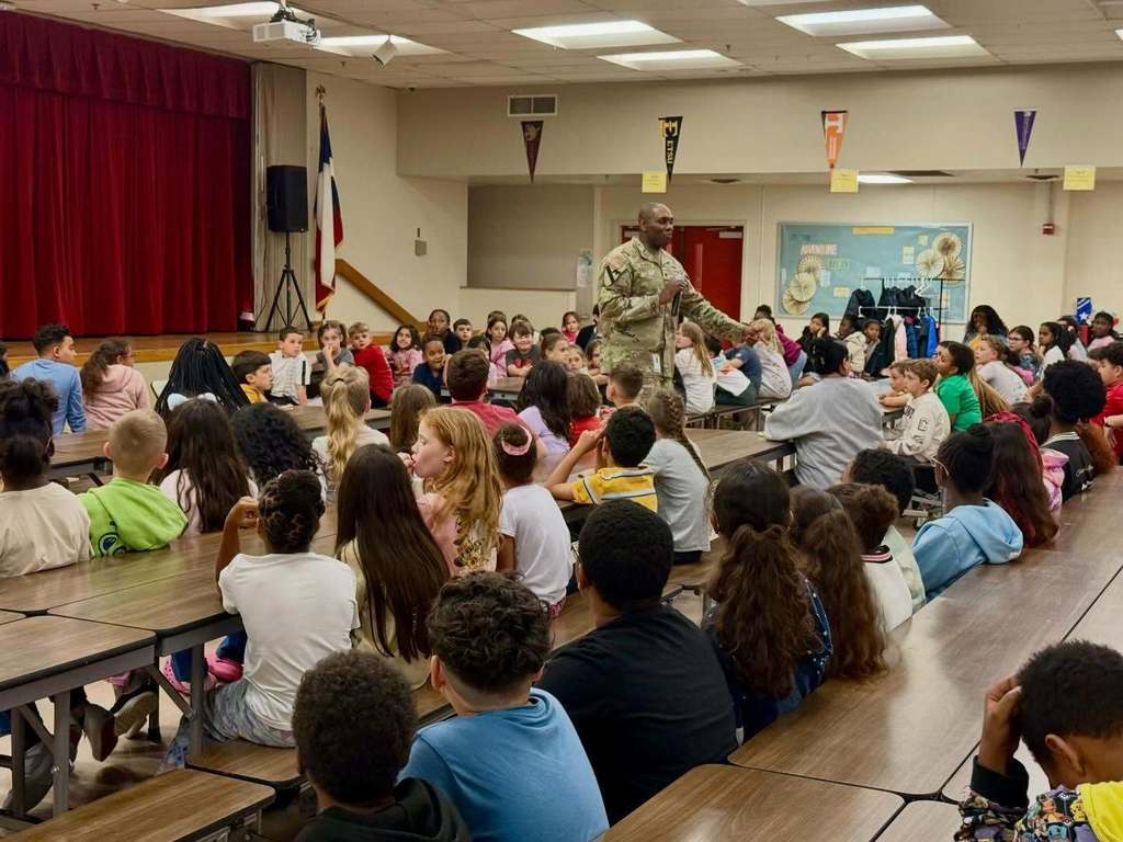 man in military uniform talking to a group of student 