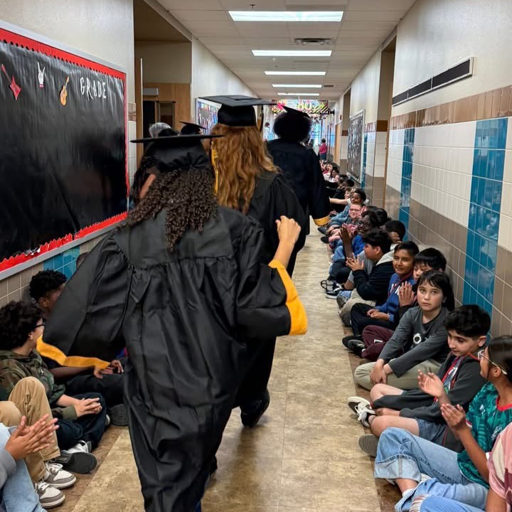 student walking the hall lined with elementary students cheering