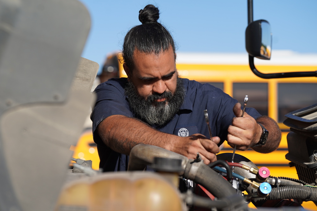 KISD employee works on a bus engine