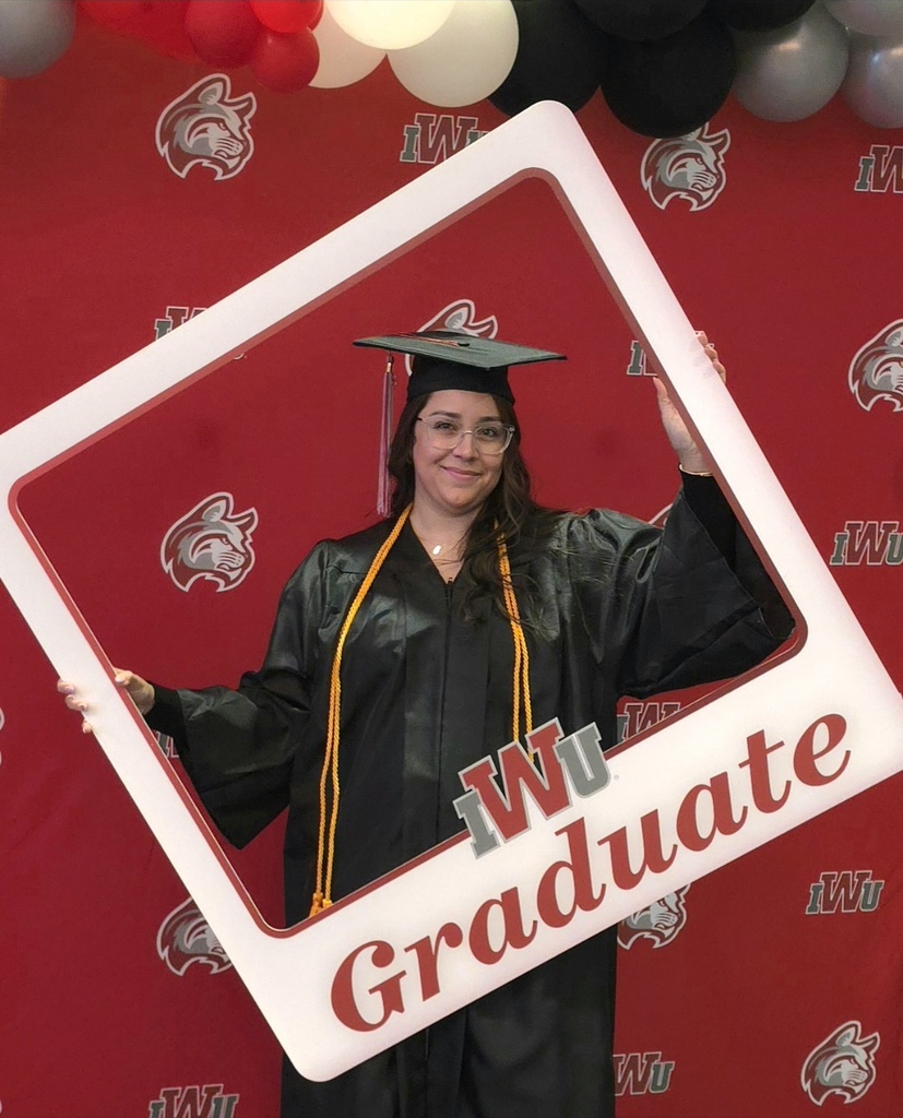 woman smiling at camera with a sign that says IWU Graduate