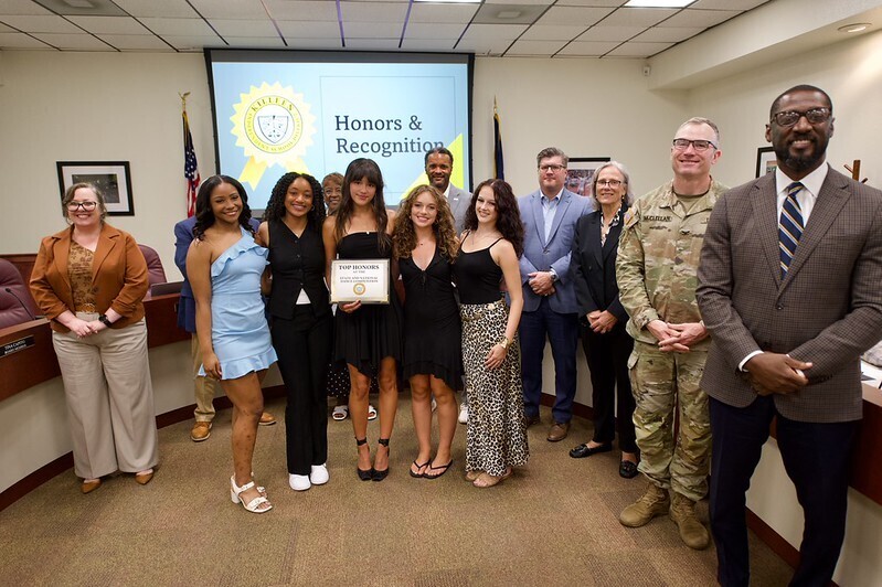 group of girlsl holding certificate with board of trustees smiling