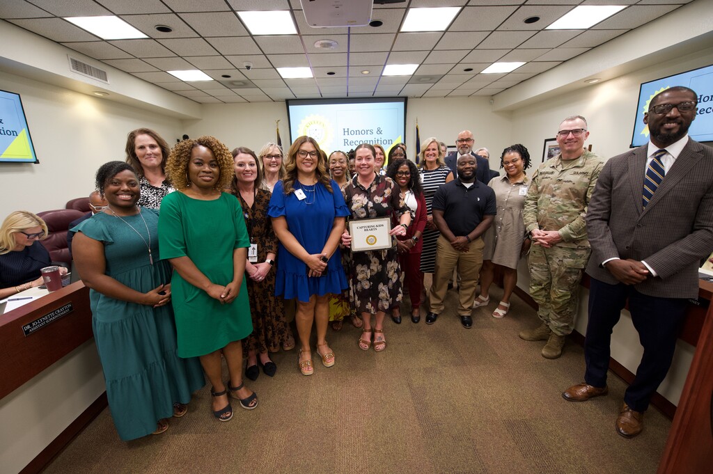 campus principals holding certificate with board of trustees smiling