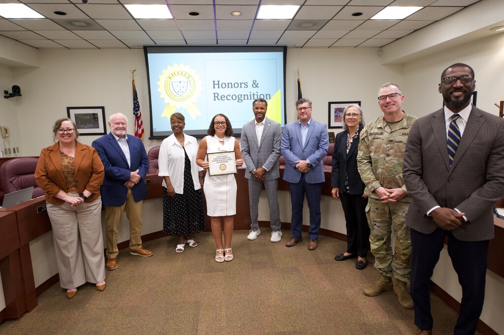 girl holding certificate with board of trustees smiling
