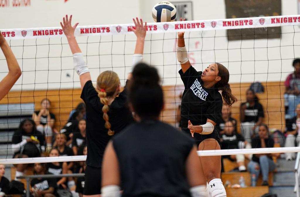 SHS volleyball player hits over the net