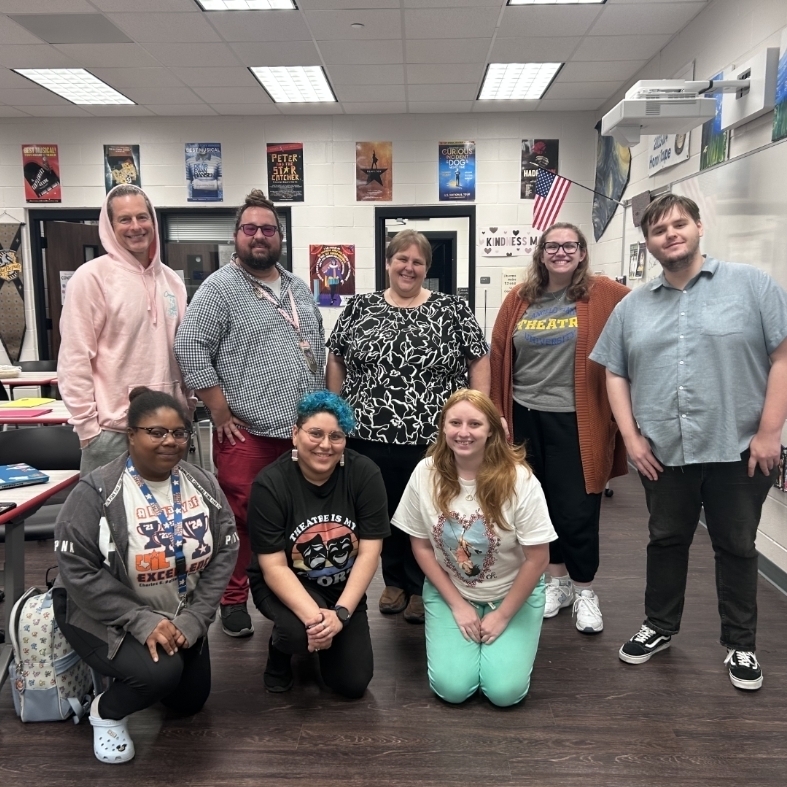 Eight teachers smiling in a classroom 