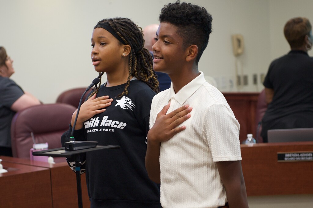 two students with their hands over their chest saying the pledge of allegiance