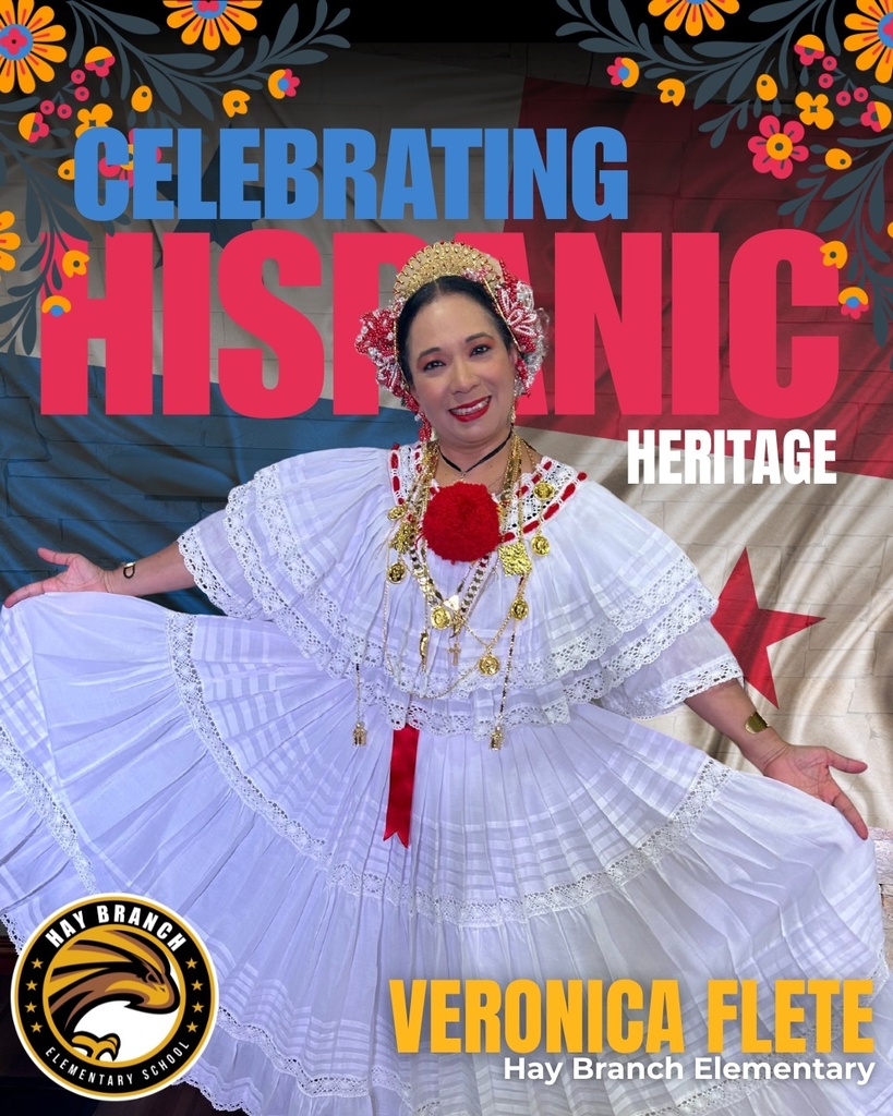 A woman in a white dress poses for a photo with a red flower in her hair.