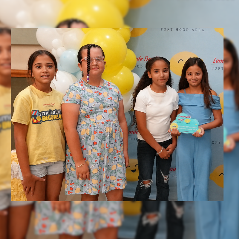 group of students smiling at camera holding their award