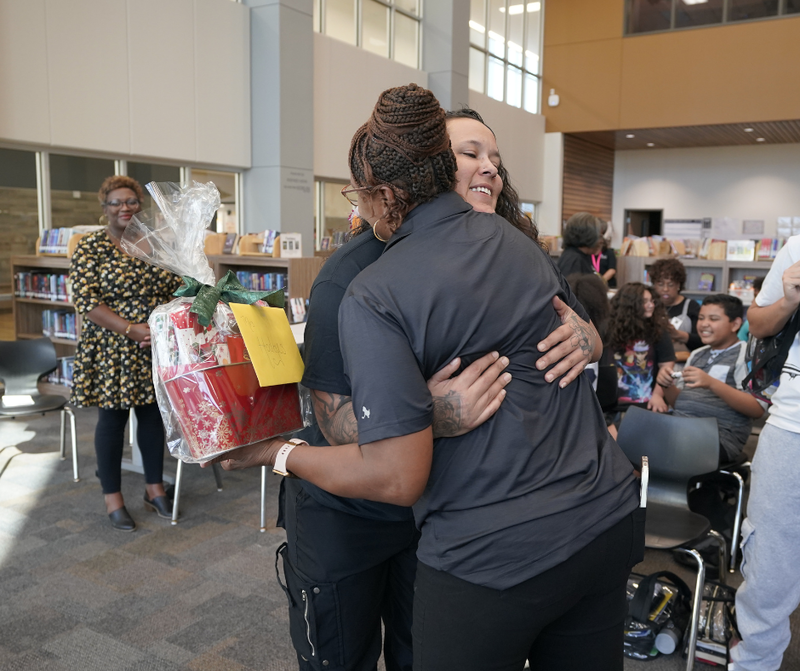 woman hugging handing a gift to another lady in the photo