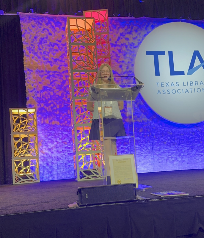 girl at the podium talking into a mic and announcing information 