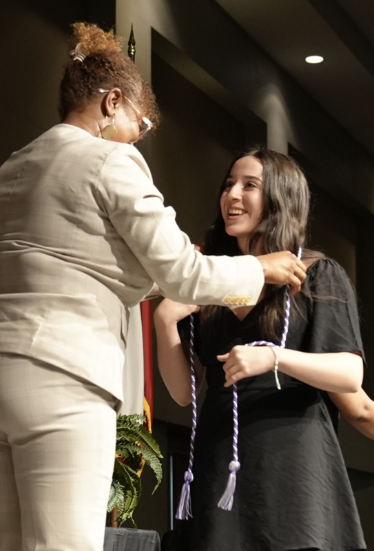 student receiving cord on stage