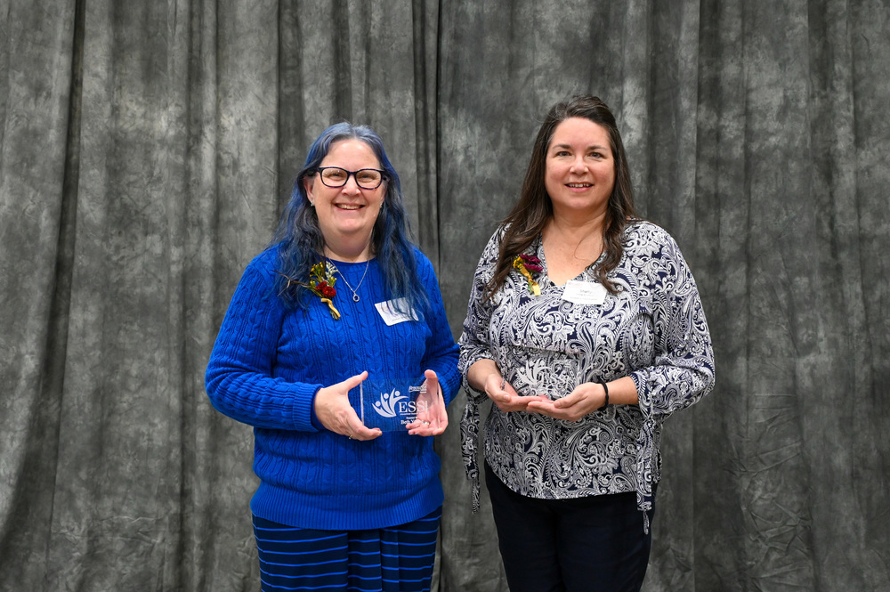 2 female award winner holding their plaques in front of a drop backgrough