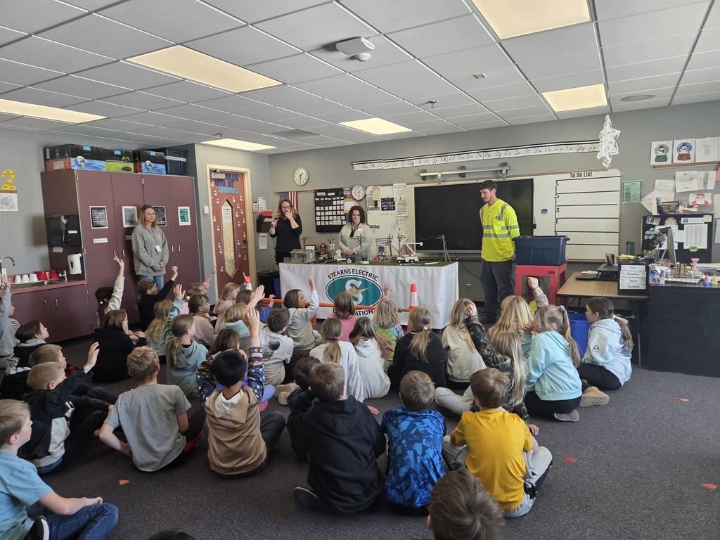 Students raising hands to answer questions from electric company presenters