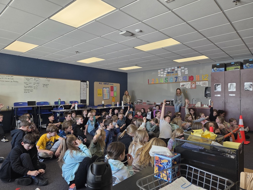 Students raising hands to answer questions from electric company presenters