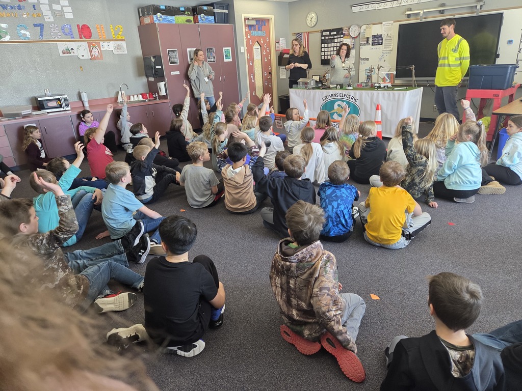 Students raising hands to answer questions from electric company presenters