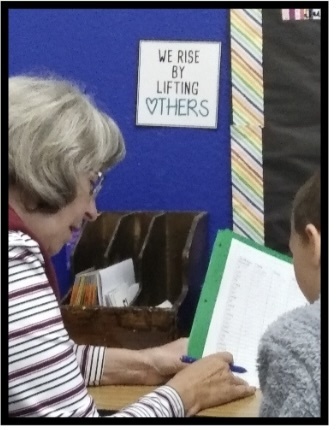 grandma carrie reading with student in halllway