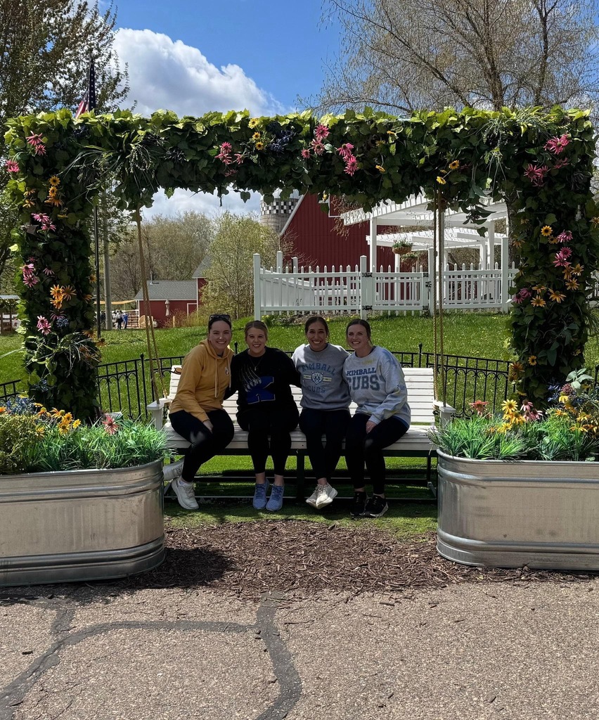 4 teachers on bench under floral arch