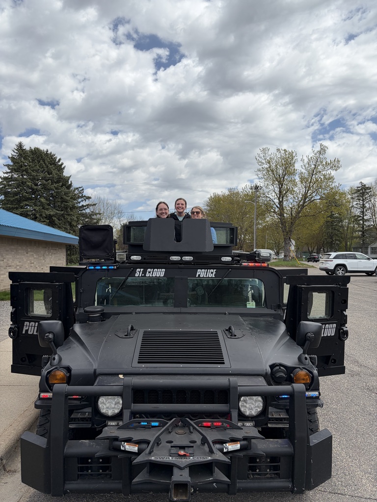 3 teachers standing in amored police vehicle