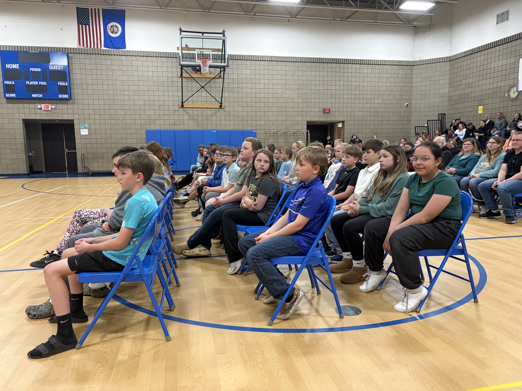 students sitting in chairs in gym