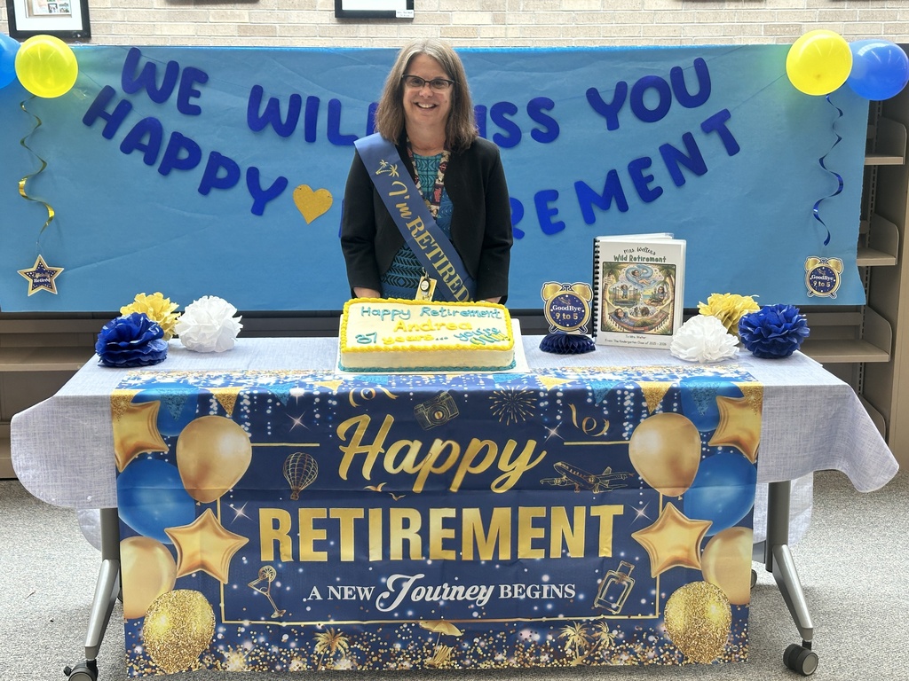 teacher standing behind table holding up cake with retirement sign in the front