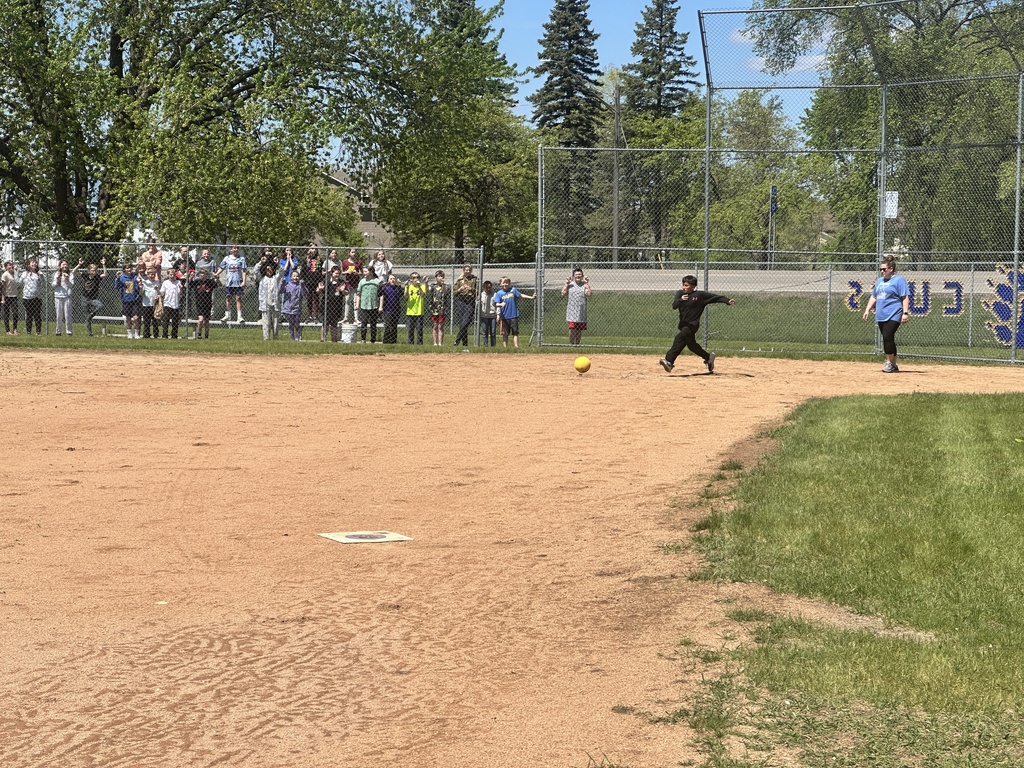 student kicking ball in kickball match