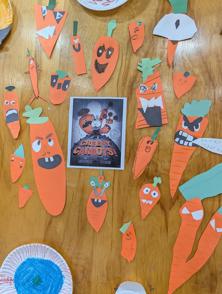 Display of paper carrots with faces attached to a table with a small movie poster.