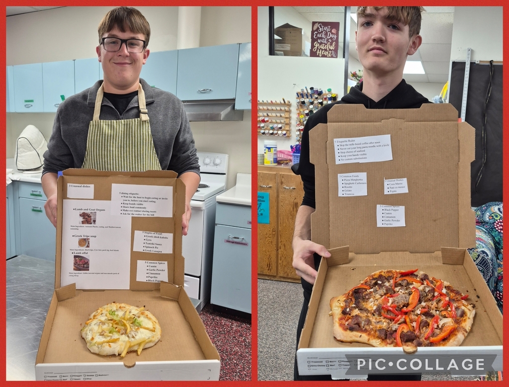 Two boys in a kitchen, each holding a pizza box with paper attached, one pizza has toppings, the other does not.