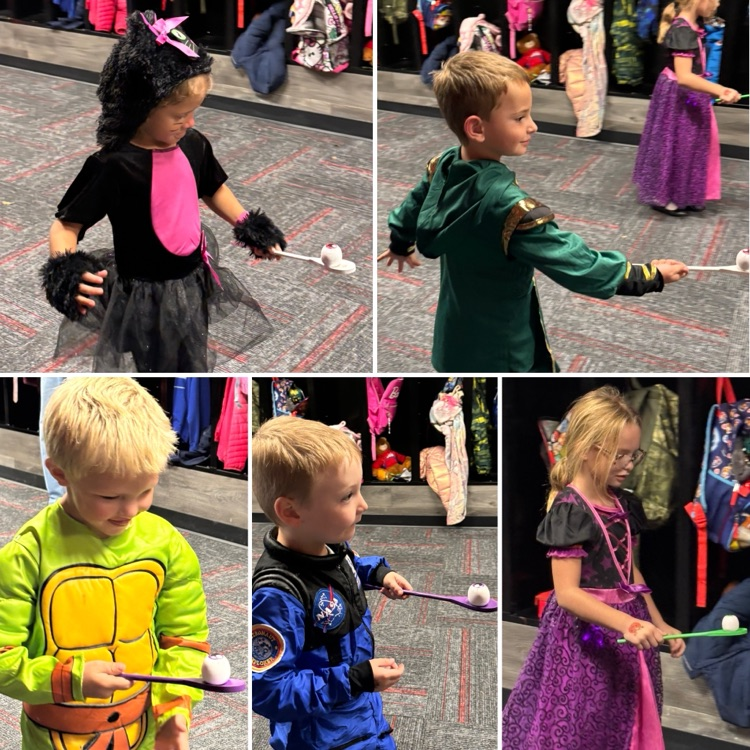 Four young children in various costumes holding sticks. Each child appears to be holding their stick as though they are fencing.