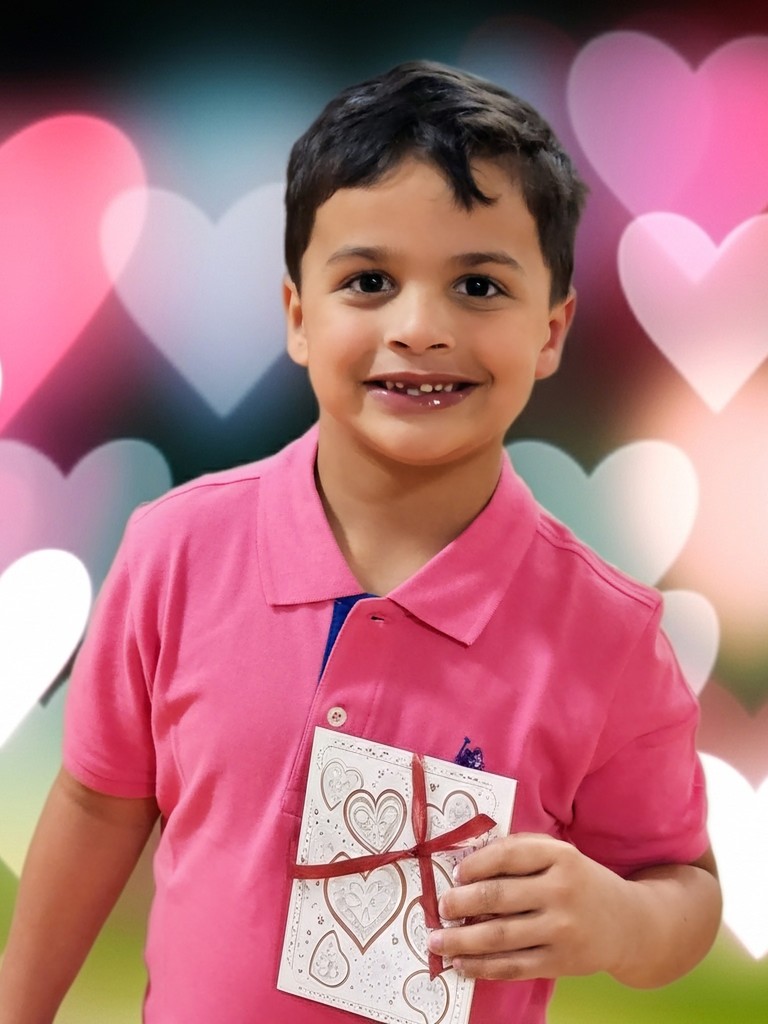 Little boy smiling with hearts in the background.