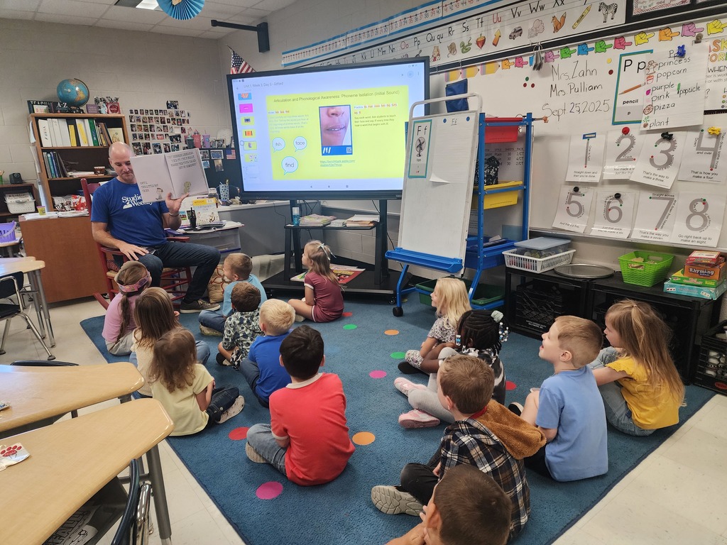 Mr. Horne reading a book to a class.