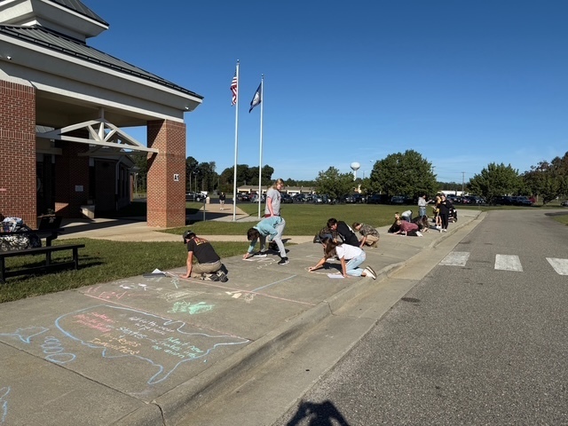 Students drawing Constitution chalk drawings at the front of the school