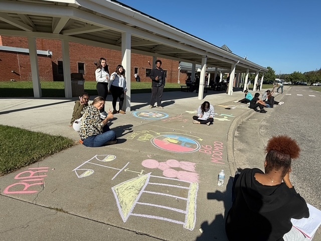 Students drawing Constitution chalk drawings at the front of the school