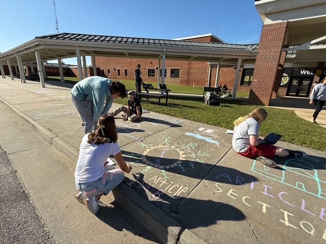Students drawing Constitution chalk drawings at the front of the school
