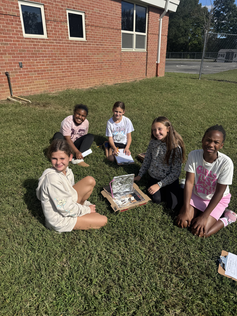 Students in grass with their solar ovens