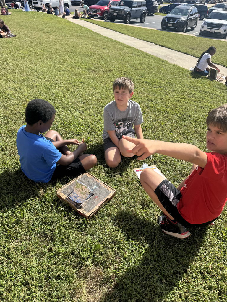 Students in grass with their solar ovens