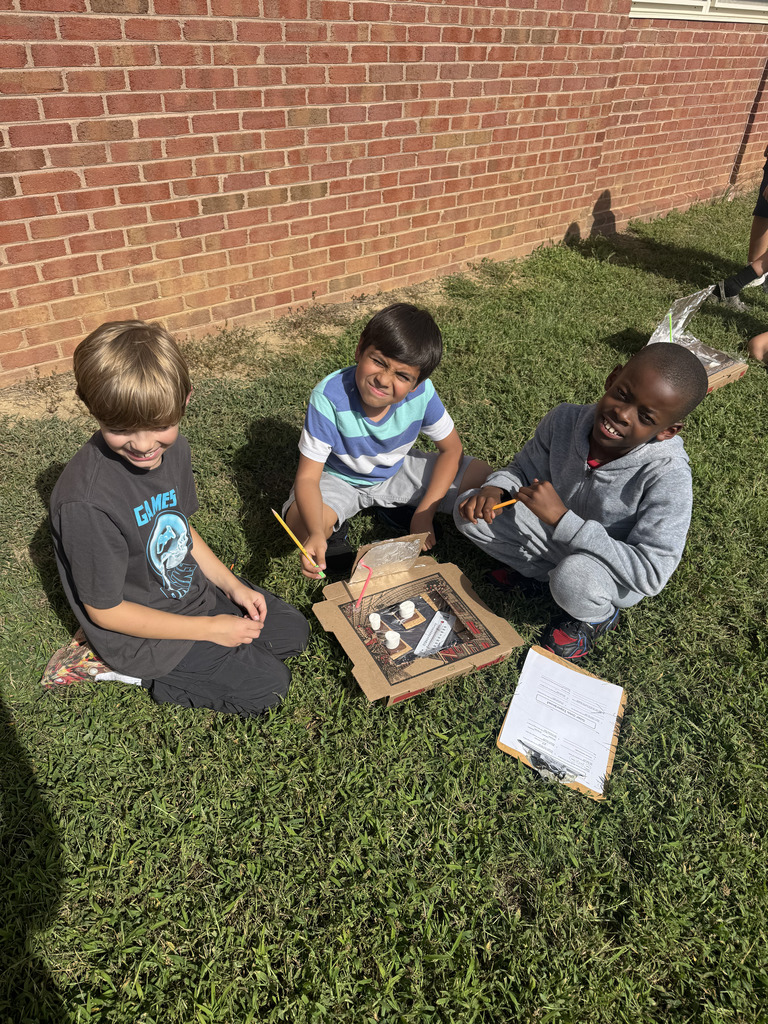 Students in grass with their solar ovens