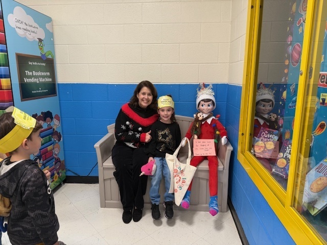 Mrs. McCullough poses on the bench with a student and a Christmas elf.