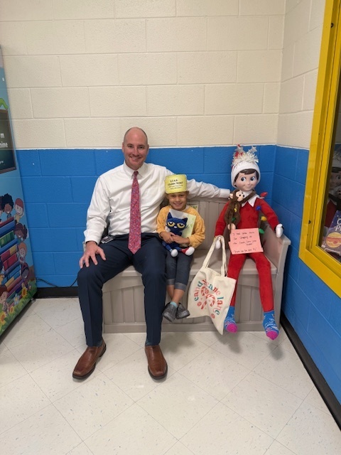 Mr. Horne poses on the bench with a student and a Christmas elf.