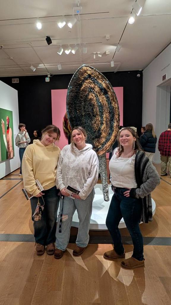 Students posing in front of art work at the Giants exhibit