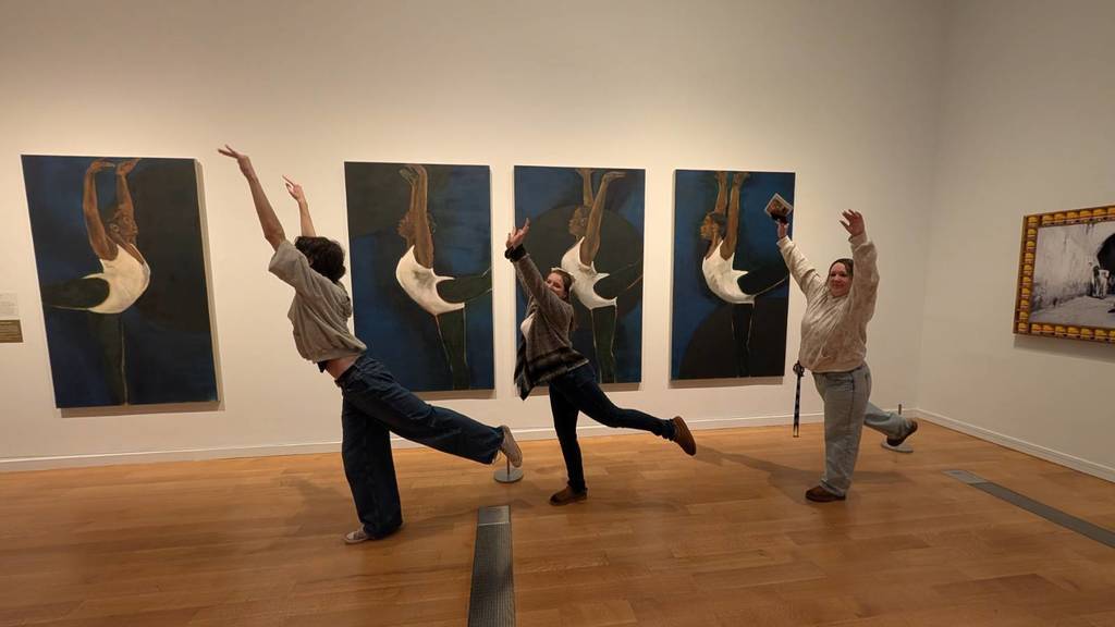 Students posing in front of art work at the Giants exhibit