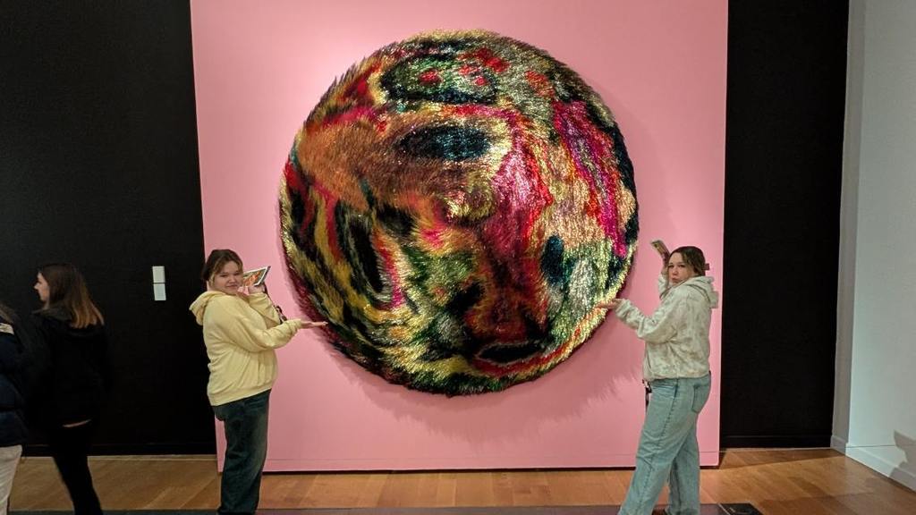 Students posing in front of art work at the Giants exhibit