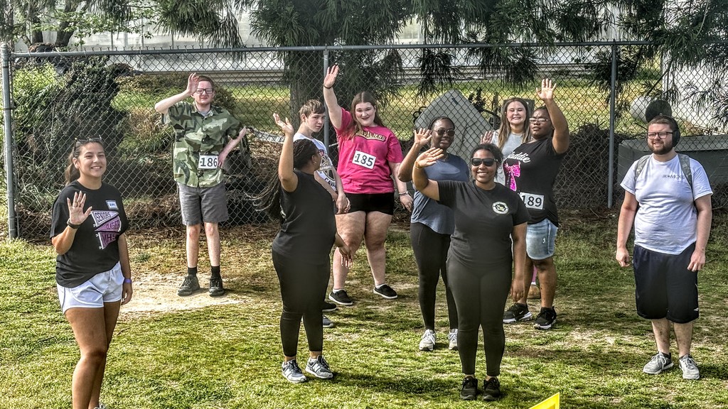 Student participants and assistants from the event waving at the camera