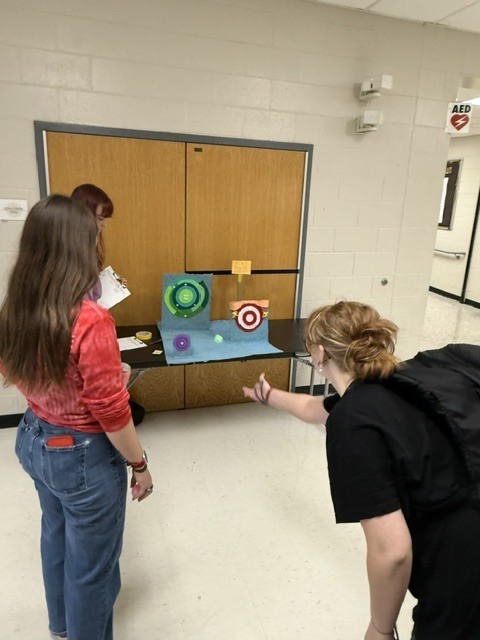 Students playing ball toss target carnival game