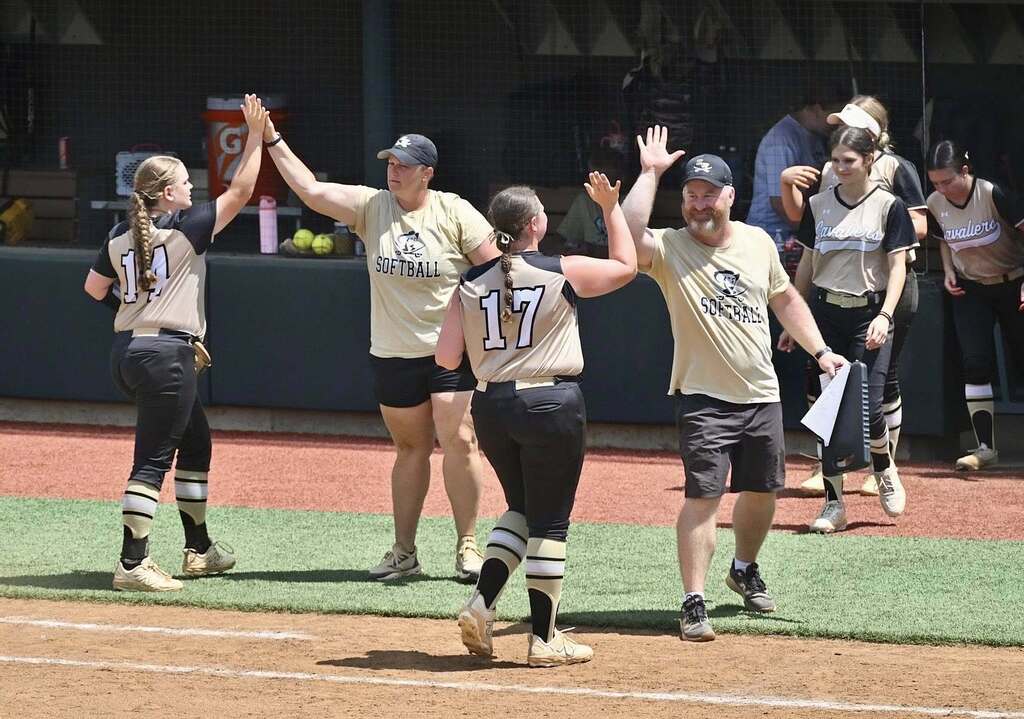 Softball team members high five their coaches