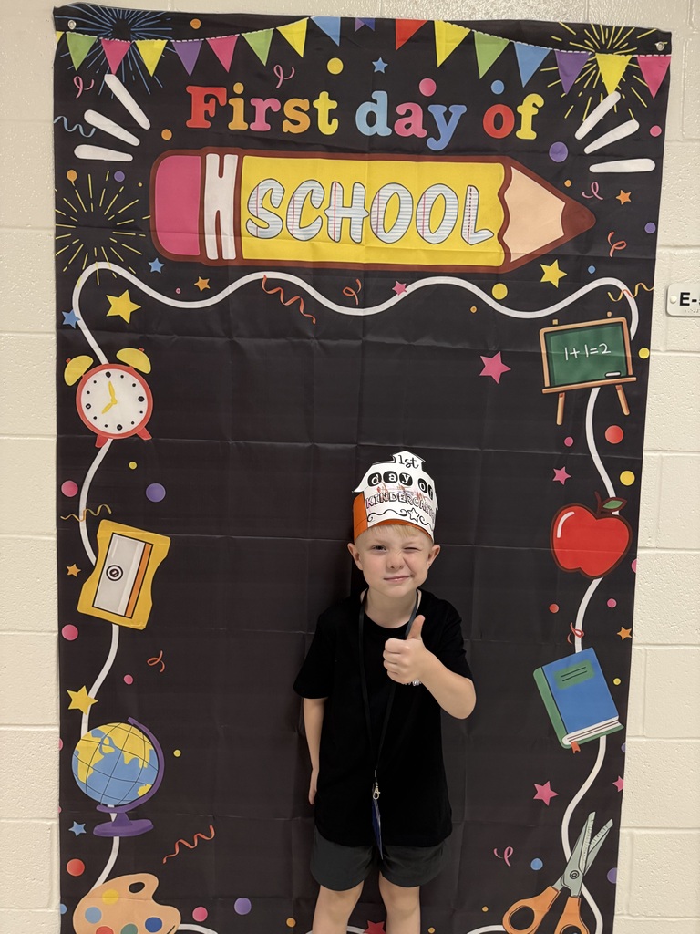 A student stands in front of the first day of school banner.
