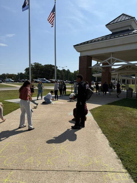 Students drawing positive messages on the sidewalk